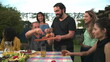 © Marco - Barbecue chef bringing food to friends and family gathered around table. BBQ chef serving food to father