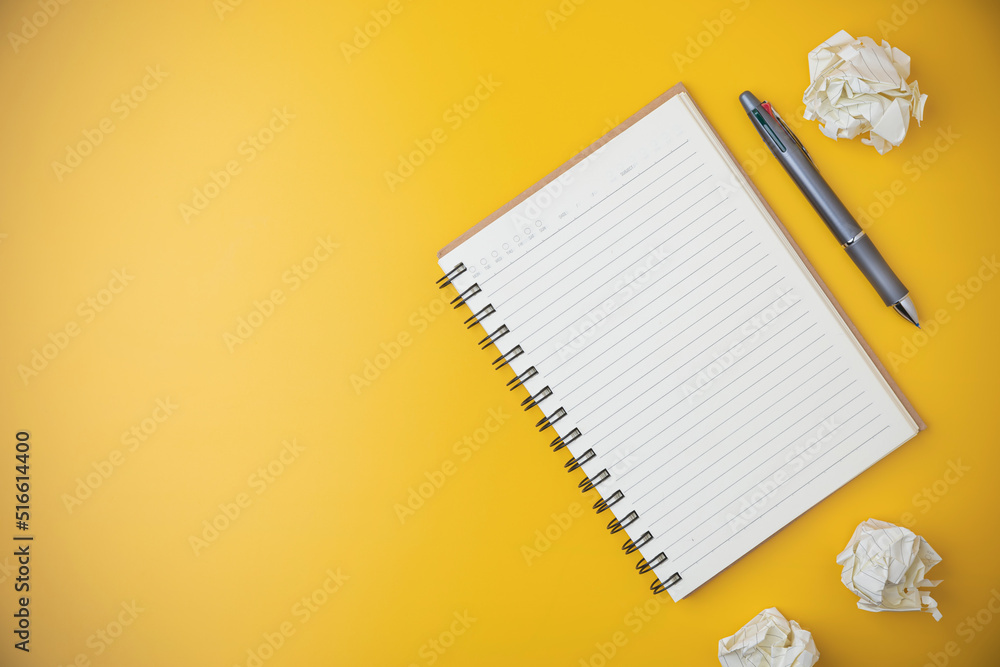 Flat lay notebook with a pen on yellow background. Business, study, and learning concept. Copy space on office workspace yellow desk.