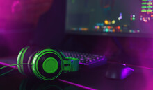 Computer Gaming Mouse And Keyboard With Purple Backlight Next To Green Headphones Opposite The Monitor.