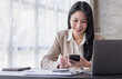 © David - Asian businesswoman using mobile phone indoor, Asian businesswoman working on laptop in modern office.