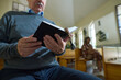 © pressmaster - Hands of senior male parishioner of Catholic church holding open Holy Bible in black leather cover with wooden rosary beads between pages