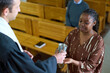 © pressmaster - Young parishioner of Cstholic church receiving cup with wine from hands of priest while taking part in communion rite during liturgy