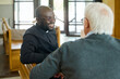 © pressmaster - Young cheerful African American pastor of evangelical church consulting aged grey haired male parishioner after sermon