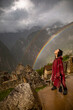Woman and two rainbows in Inca citadel called Machupichu built of stones in the mountain, cloudy day, Peru