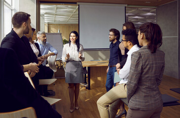 Wall Mural - Confident businesswoman head lead meeting with diverse businesspeople in office. Successful female team leader or boss talk with multiethnic team at briefing. Leadership and teamwork.