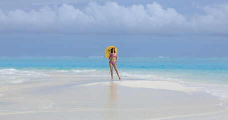 Canvas Print - girl in a bikini with a yellow umbrella on the sea sand