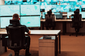 Wall Mural - Male security operator working in a data system control room offices Technical Operator Working at workstation with multiple displays, security guard working on multiple monitors Male computer opera