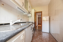 Long And Narrow Kitchen With Furniture To One Side And A Solitary Refrigerator
