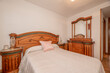 Bedroom with double bed with tacky wooden headboard in a room with oak floor and matching chest of drawers with mirror
