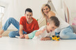 © PoppyPix - parents playing with a car with their little son at home. High quality photo
