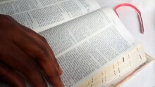 An African Lady's Hand Holding A Blue Colored Pencil, Looking And Finding A Bible Verse Then Marking It By Underlining Text. Flipping. Placing Red Ribbon Book Mark. Christianity Concept