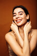 © iordani - Cute happy young indian woman on brown background in studio close up smiling, fashion beauty warm tanned