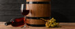 Barrel, bottle and glass of wine on wooden background