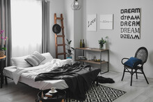 Interior Of Stylish Bedroom With Posters And Shelving Unit