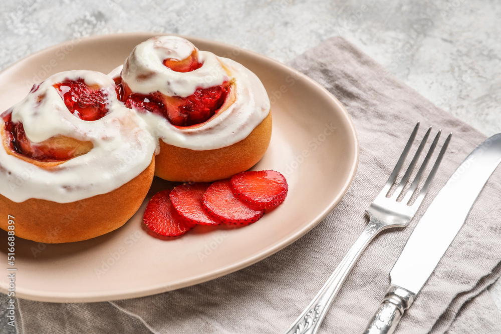 Plate with strawberry cinnamon rolls and cream on grunge background, closeup