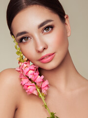 Wall Mural - Portrait beautiful young woman with clean fresh skin. Model with healthy skin, close up portrait. Cosmetology, beauty and spa. Girl with a pink  flower