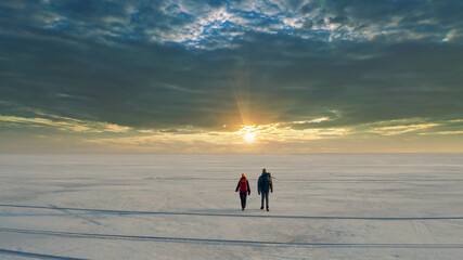 The two people with backpacks going through the snow field