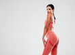 © halayalex - Tanned fitness woman in pink sports clothing. Sexy young beautiful model with perfect body.Female isolated on grey background in studio. Stretching out before training