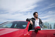 © Manuel - Handsome young man with beard, sunglasses, leather jacket and white shirt, leaning on the roof of his red sports car. Concept beauty, fashion, trend, luxury, motor, sports.