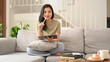 © Prathankarnpap - Charming asian woman using digital tablet on couch in cozy living room, enjoying leisure weekend time alone at home