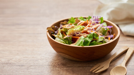 Wall Mural - mix salad from green leaves and cherry tomato in a wooden bowl with a spoon and fork on white wood table background. copy space