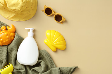 Baby sun safety concept. Sunscreen cream bottle, sun glasses, sand molds, towel, panama hat on beige table. Flat lay, top view.