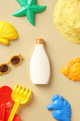 Sunscreen bottle with summer kids accessories on beige table. Baby sun protection concept.