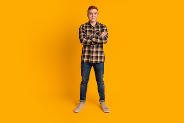 Poster - Portrait of a happy casual man stand with arms folded over yellow background isolated