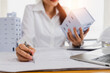 © khwanchai - close up hand of engineer architect woman check correction on blue print and holding building model