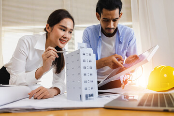 Asian engineer woman point on building model and man check on solar cell for install on top, professional smart architect prepare for smart eco and pure power concept