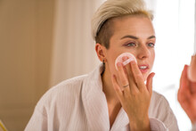 Short Haired Attractive Woman Cleaning Her Face With Cotton Pad While Taking Care Of Her Skin