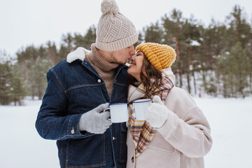 Wall Mural - people, season, love, drinks and leisure concept - happy couple with tea cups in snowy winter park