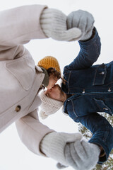 Canvas Print - people, love and leisure concept - happy smiling couple holding hands and kissing in winter park from below