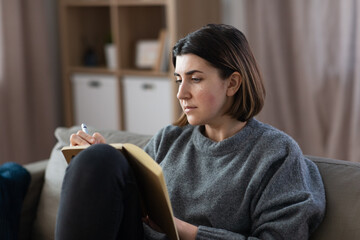 Wall Mural - stress, mental health and depression concept - sad crying woman with diary sitting on sofa at home