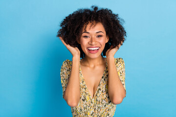 Photo of pretty excited woman wear print dress arms hairdo smiling isolated blue color background