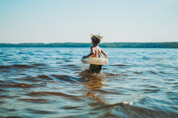 cute caucasian boy running into water with splashes and laughter. Vacation on sea side. Happy childhood. Image with selective focus