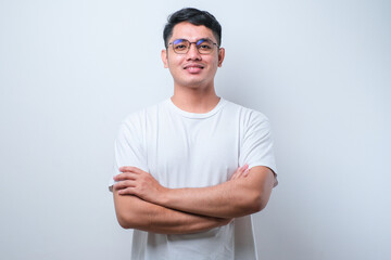 Wall Mural - Potrait of young handsome Asian man wearing casual shirt and glasses, happy face smiling with crossed arms looking at the camera