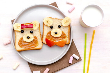 Funny cute bear,dog faces sandwich toast bread with peanut butter, banana, apple,milk, marshmallow. Kids childrens baby's sweet dessert healthy breakfast lunch food art on plate,close up,top view