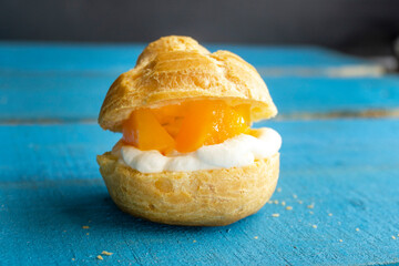 Wall Mural - Cream puffs with peach on a blue background. food concept. eclair profiteroles