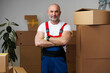 © fotofabrika - Portrait of a middle-aged man mover in uniform standing against stacked boxes