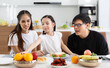 © atitaph - A happy Asian family spends lunch, vegetables, fruit, and dates at the table in their home. Cute little daughter having fun talking. Father, mother