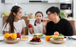 © atitaph - A happy Asian family spends lunch, vegetables, fruit, and dates at the table in their home. Cute little daughter having fun talking. Father, mother