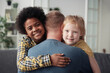Portrait of happy multiethnic children smiling at camera while embracing their foster dad