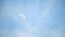 Half Moon Against Blue Sky With Moving Clouds
