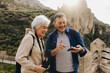 © JLCo Ana Suanes - Carefree senior couple having a video call while hiking outdoors