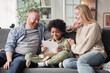 © AnnaStills - Happy child reading a letter about adoption while sitting on sofa with his foster parents