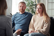 © AnnaStills - Young foster couple listening to briefing of social worker before adoption of child during their meeting at home