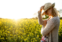 Portrait Of A Girl With A Straw Hat In A Rapeseed Field At Sunset