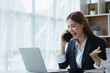 © kamiphotos - Asian woman talking on the phone, she is a salesperson in a startup company, she is calling customers to sell products and promotions. Concept of selling products through telephone channels.