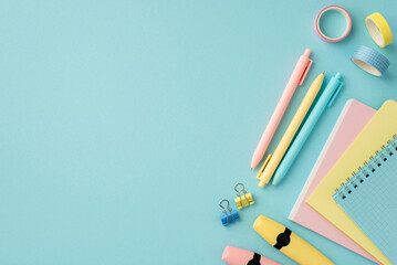 Wall Mural - Back to school concept. Top view photo of school supplies notepads pens adhesive tape binder clips and marker pens on isolated pastel blue background with copyspace